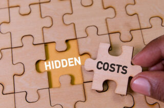 Hand placing a puzzle piece labelled hidden costs into an incomplete puzzle, symbolising unseen challenges in relocation and global mobility programmes.