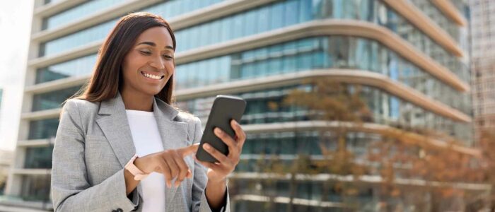 African businesswoman using a mobile phone for digital financial transactions, representing Kenya’s mobile money ecosystem and financial innovation.